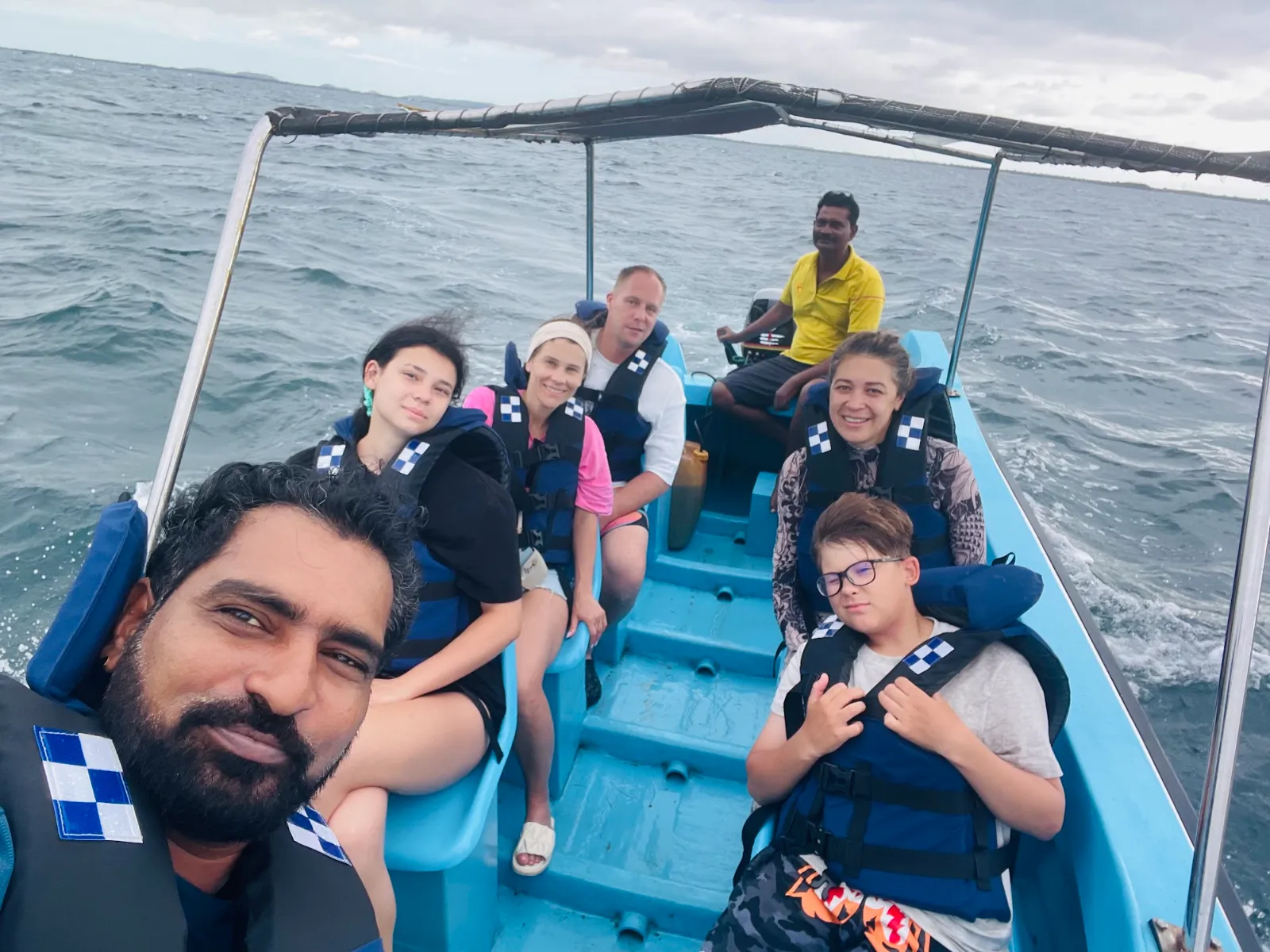 Guests in life jackets in a small blue boat out on the open sea