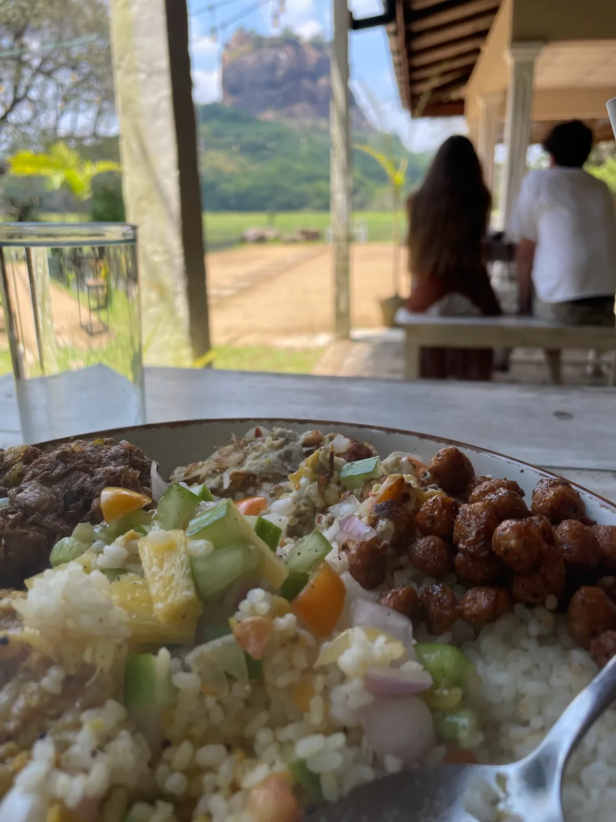 A plate of Sri Lankan rice and curry with Sigiriya rock in the distance