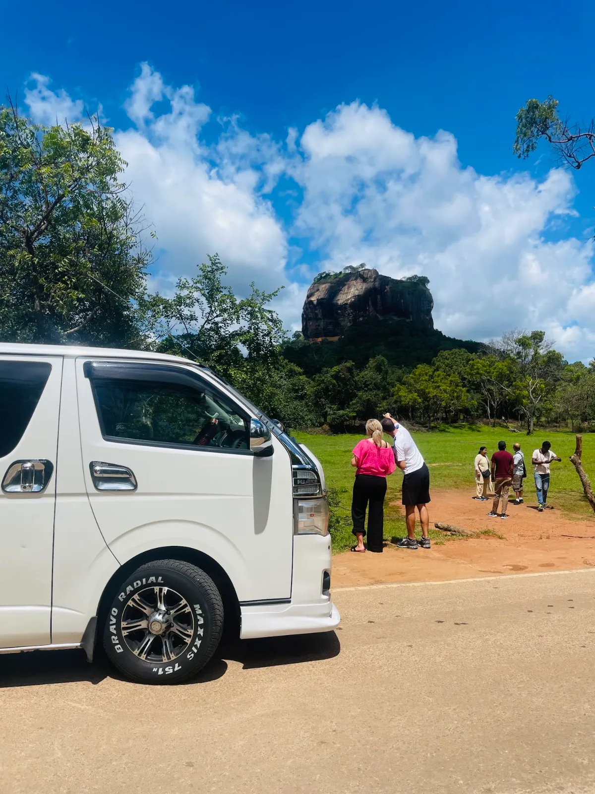 Travel Safe Lanka's white van parked with Sigiriya rock in the background